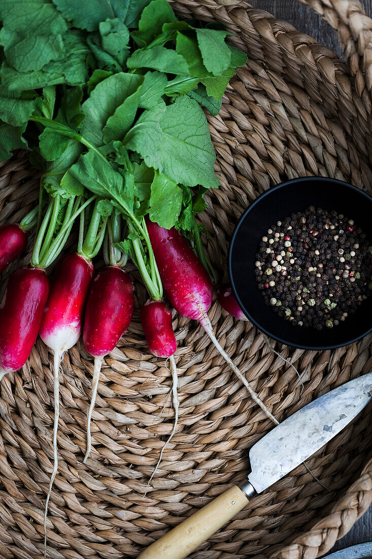 french breakfast radishes in a basket with a knife