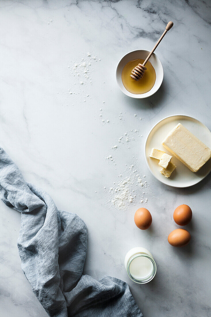 Butter eggs milk and honey on a marble kitchen counter