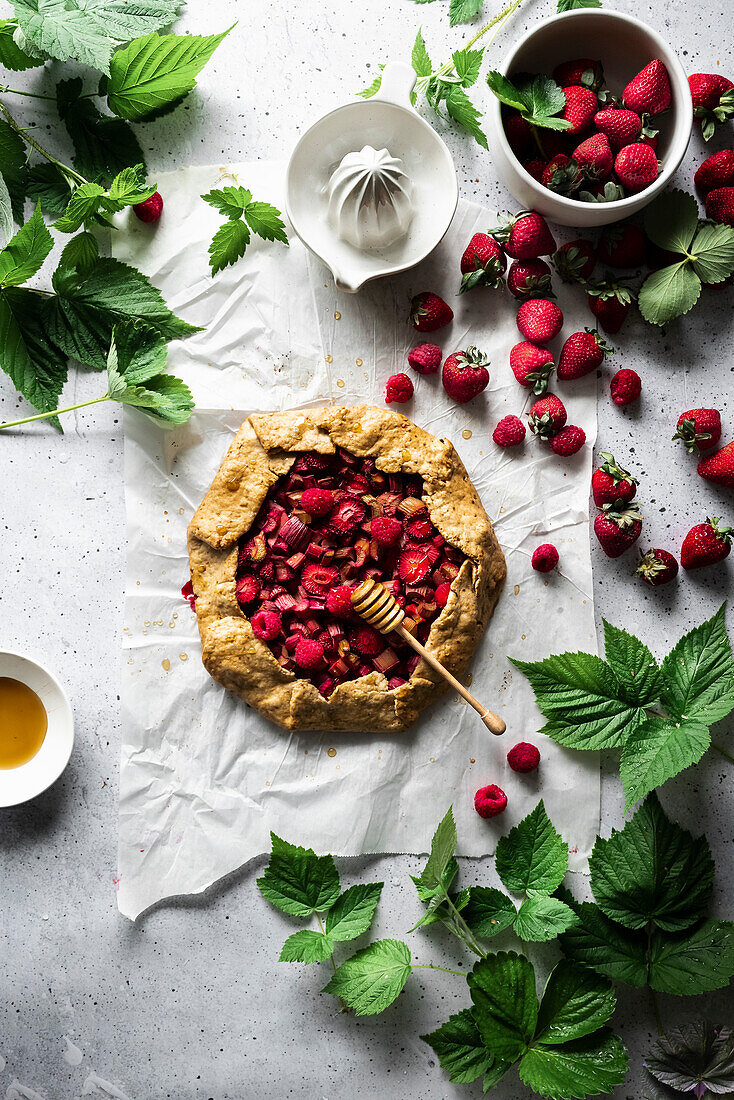 Summer berry galette on a white surface with greenery.