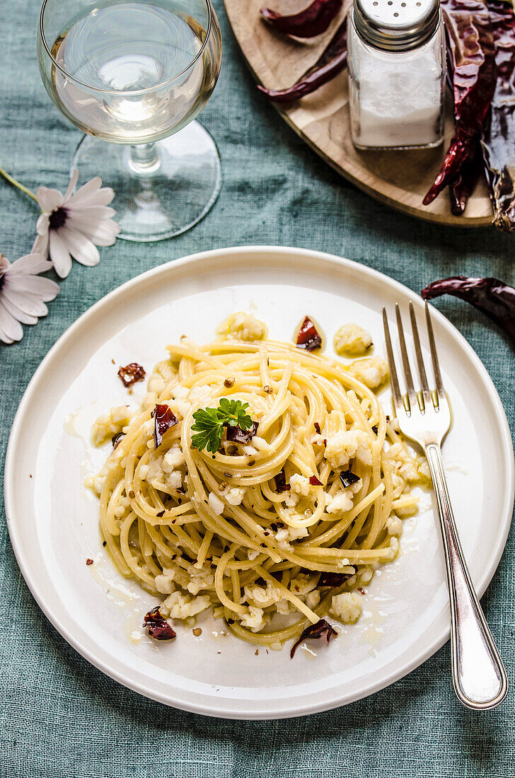 Spaghetti with salted codfish and chilli pepper, on a white ceramic plate