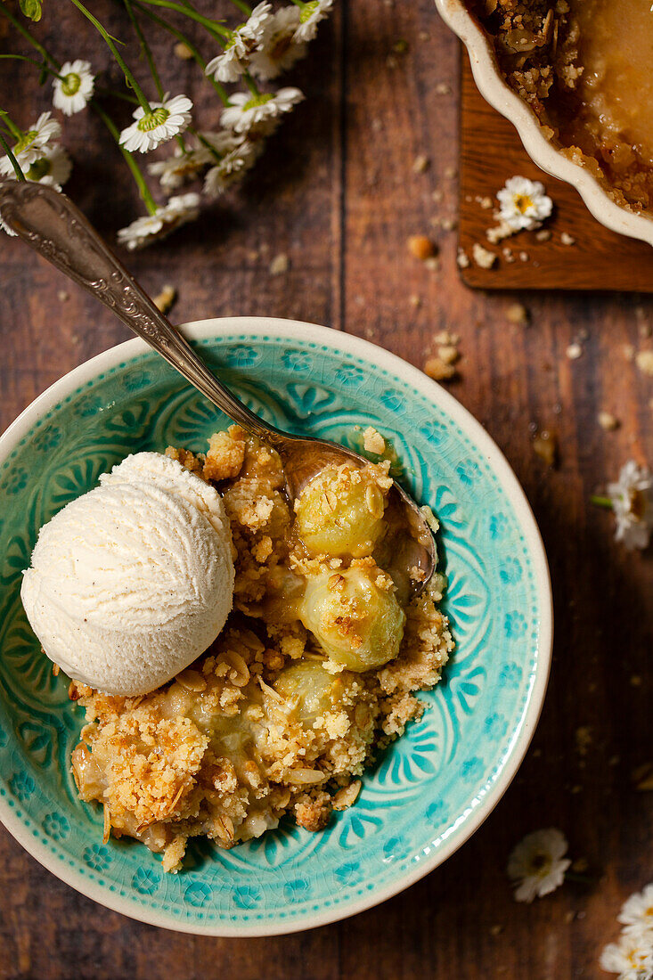 A bowl of gooseberry crisp with a scoop of ice cream on top