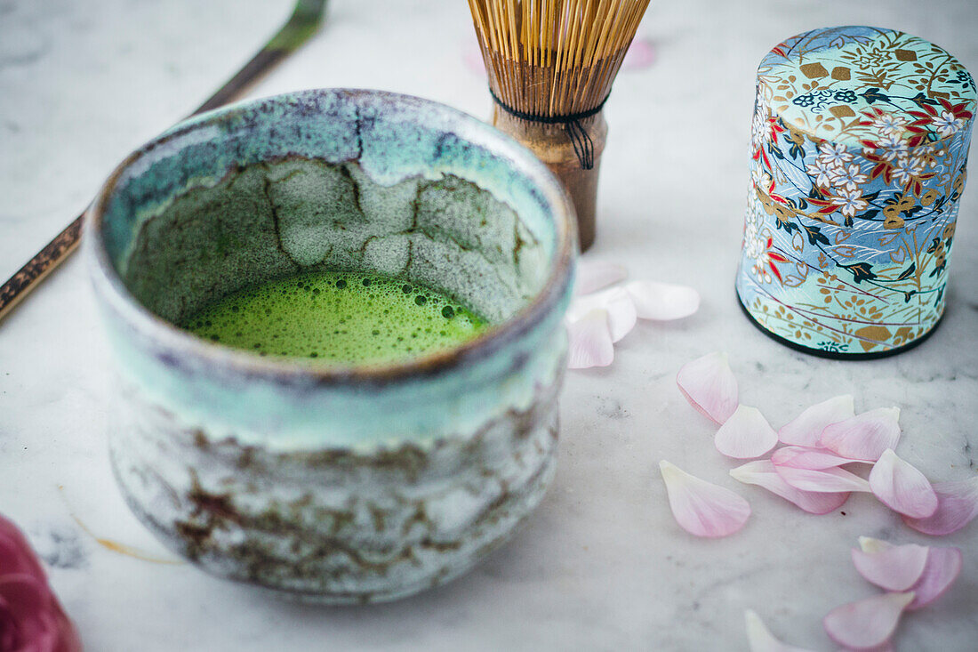 Matcha tea in tea bowl with matcha whisk and tea caddy