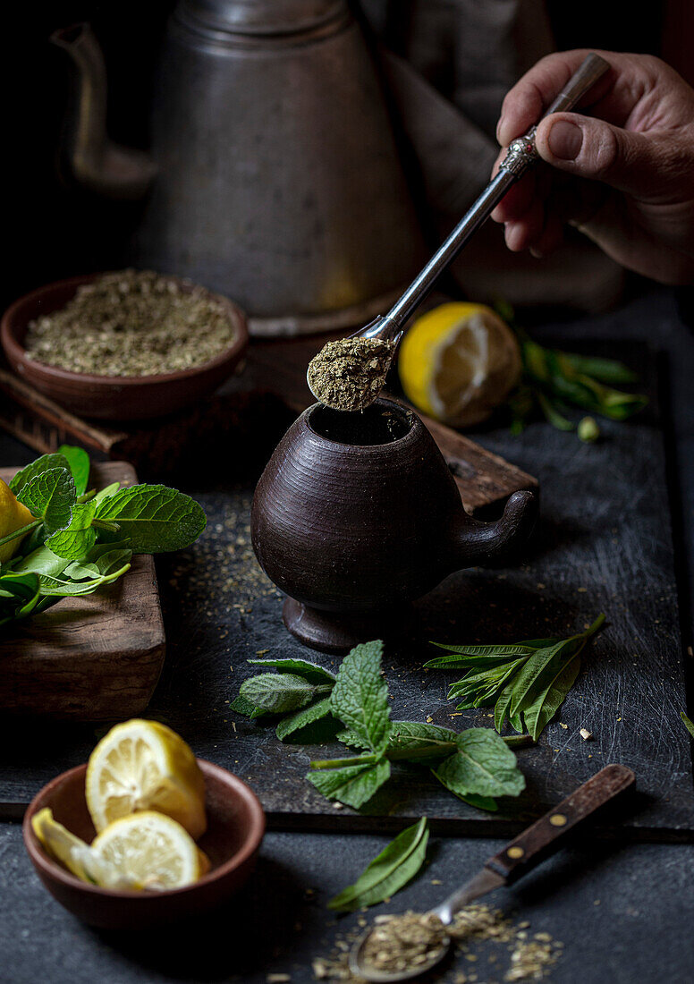 Latin American hot drink yerba mate in clay cup, herbs and lemon