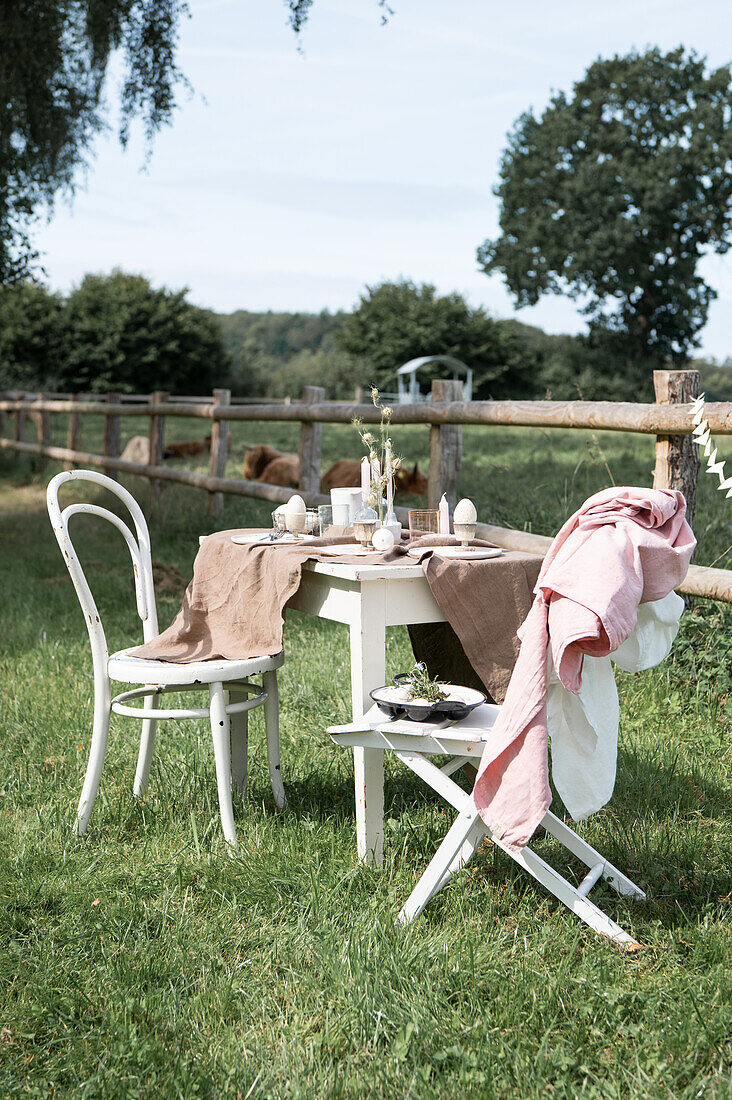 Easter table set with linen tablecloth and chairs in garden