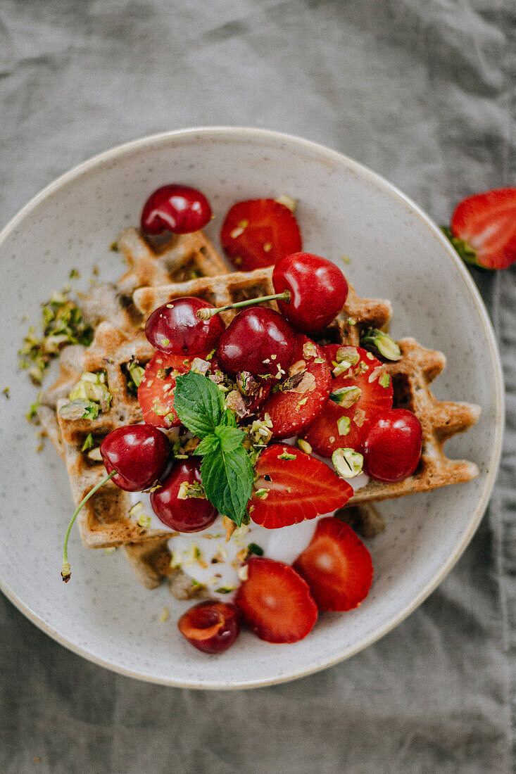 Waffles with cherries, strawberries and pistachios