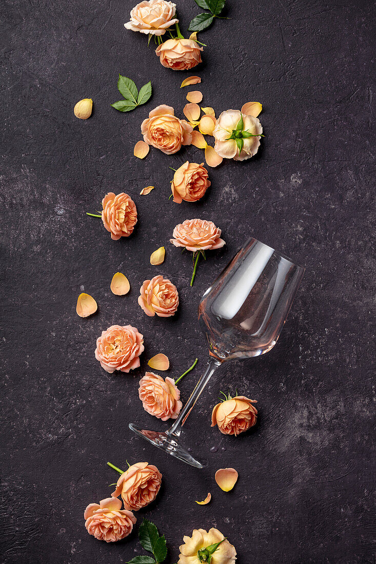Leeres Weinglas und Rosen auf dunklem Hintergrund