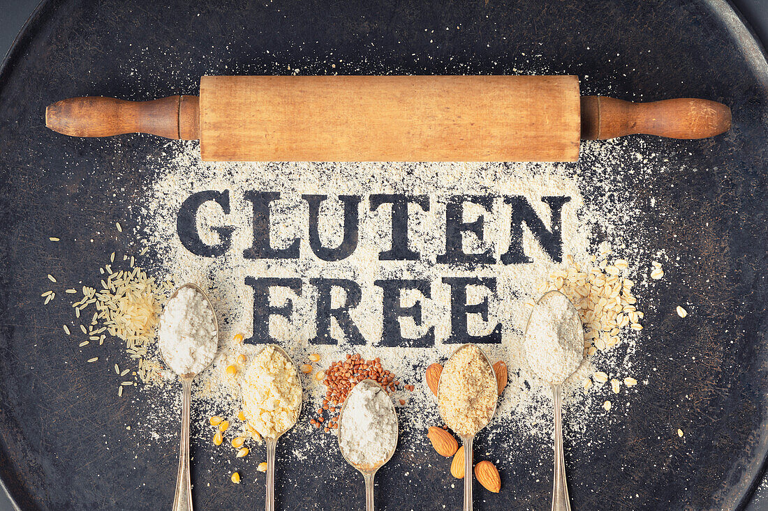 'Gluten free' Schriftzug in Mehl und Löffel mit verschiedene glutenfreien Mehlsorten