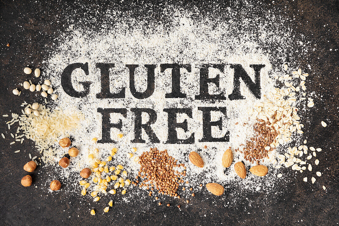 'Gluten free' Schriftzug in Mehl sowie glutenfreie Körner und Nüsse