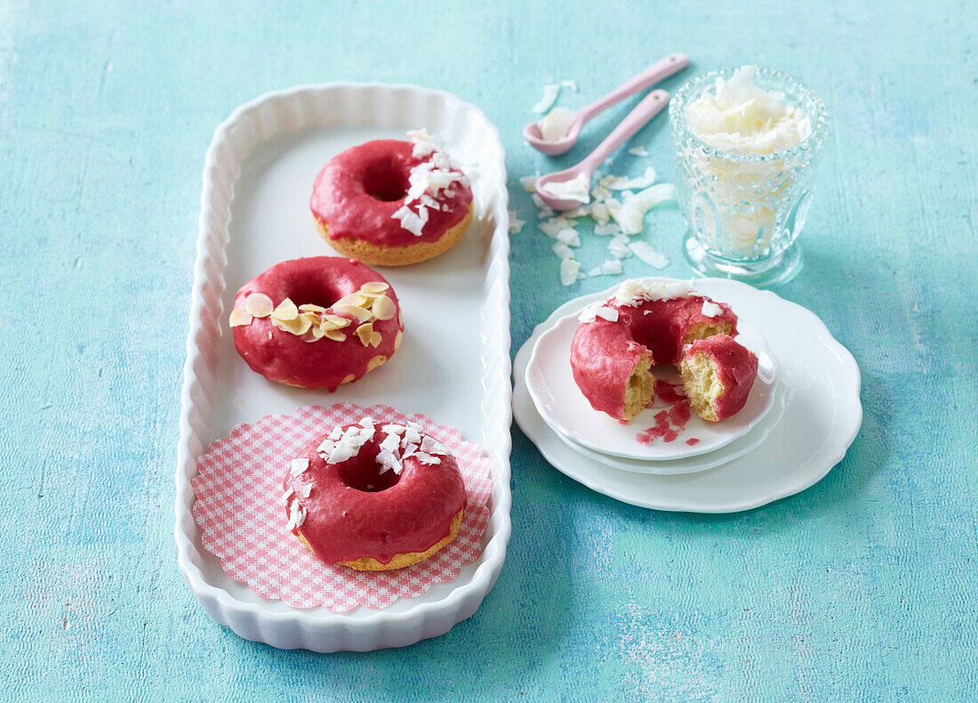 Baked donuts with raspberry glaze and coconut flakes