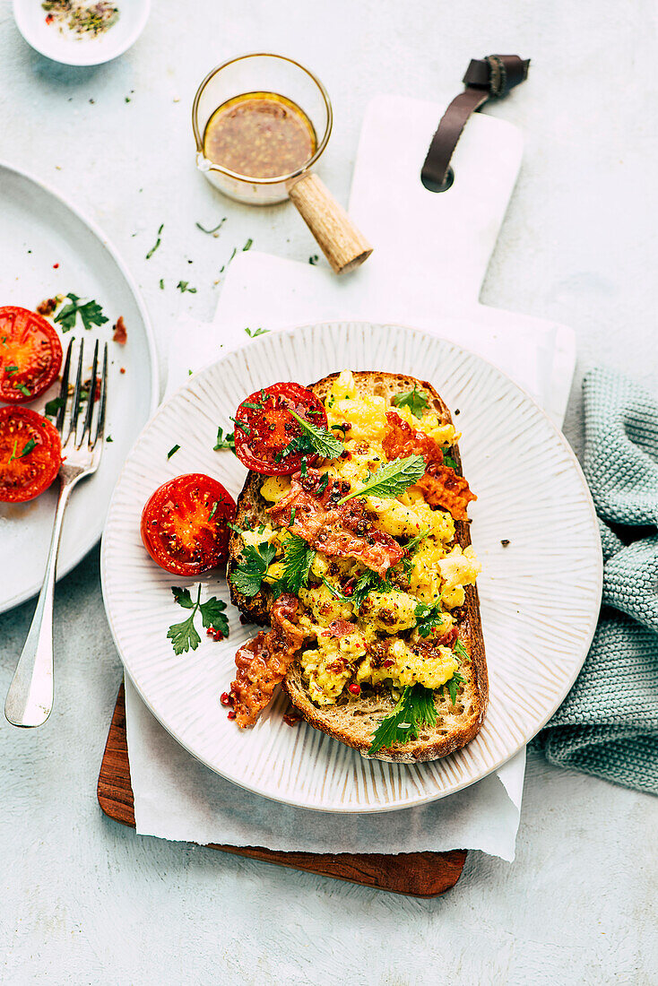 Scrambled eggs, bacon and grilled tomatoes on toast