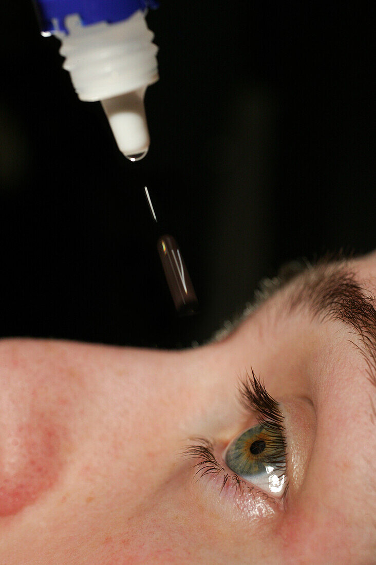 Young man applying eye drops