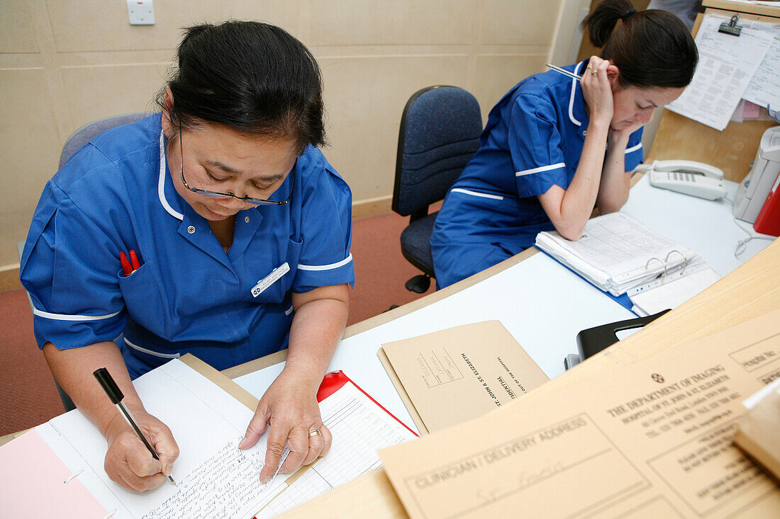 Two hospital nurses filing patient notes