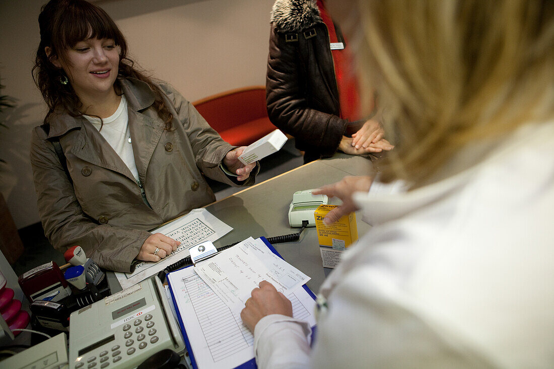 Pharmacy technician handing a prescription drug to a patient