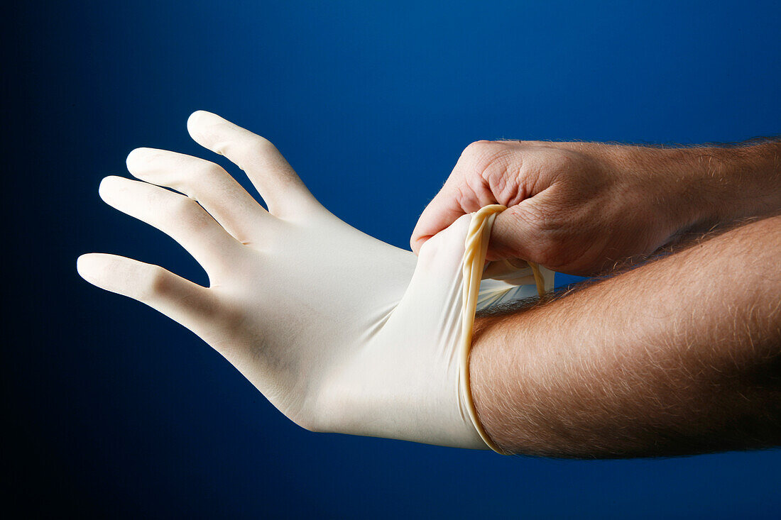 Man putting on a pair of protective latex gloves