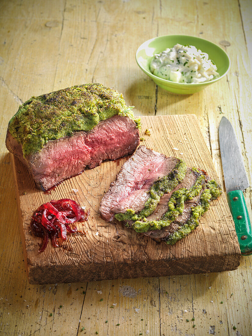 Roast beef with a herb crust on a wooden board