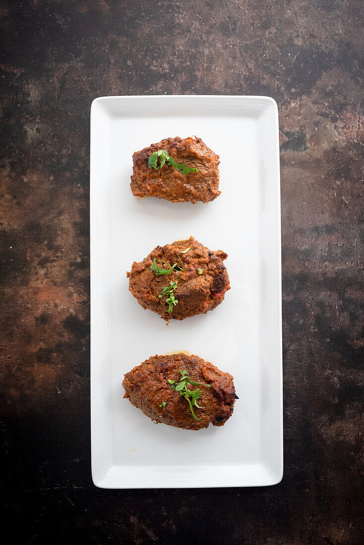 Tandoori beef tikka on a serving platter against a dark background