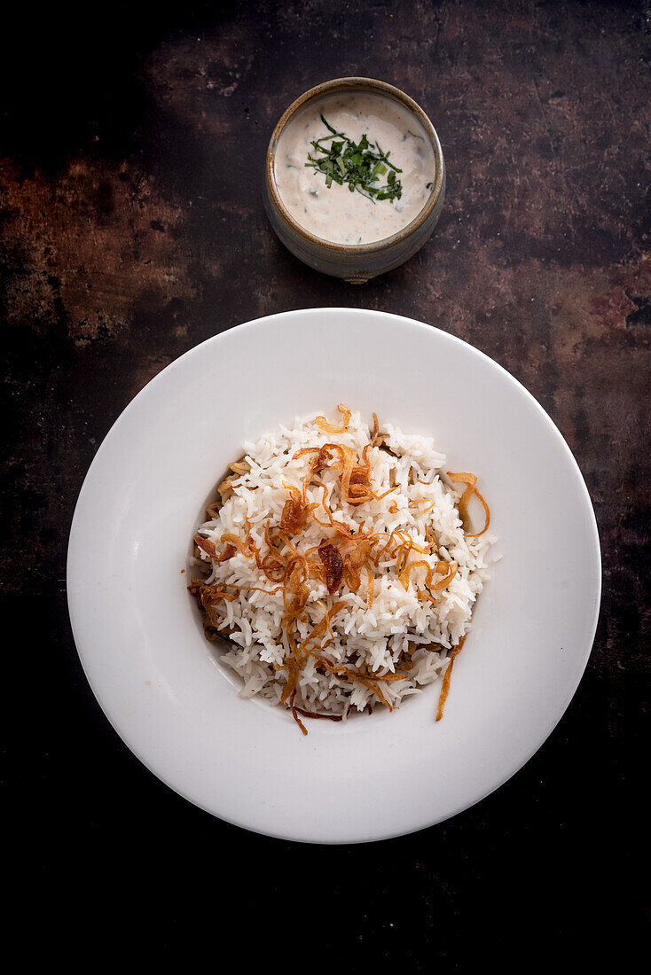 Indischer Reis mit Raita auf dunklem Hintergrund