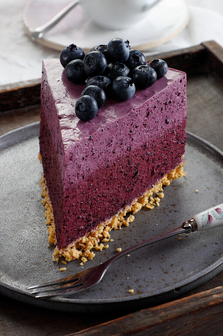 Ein Stück Frischkäse-Sahnetorte mit Blaubeeren