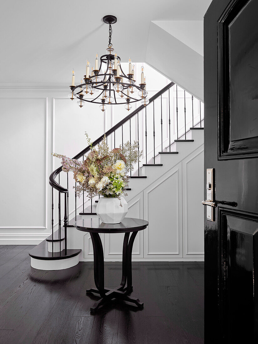 Round table with bouquet of flowers and chandelier in elegant entrance hall