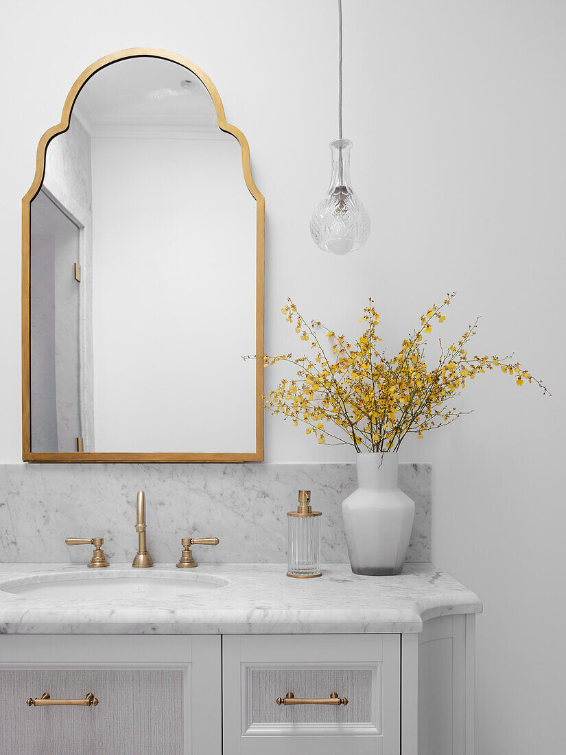 Washbasin with marble top, gold-framed mirror above in the bathroom