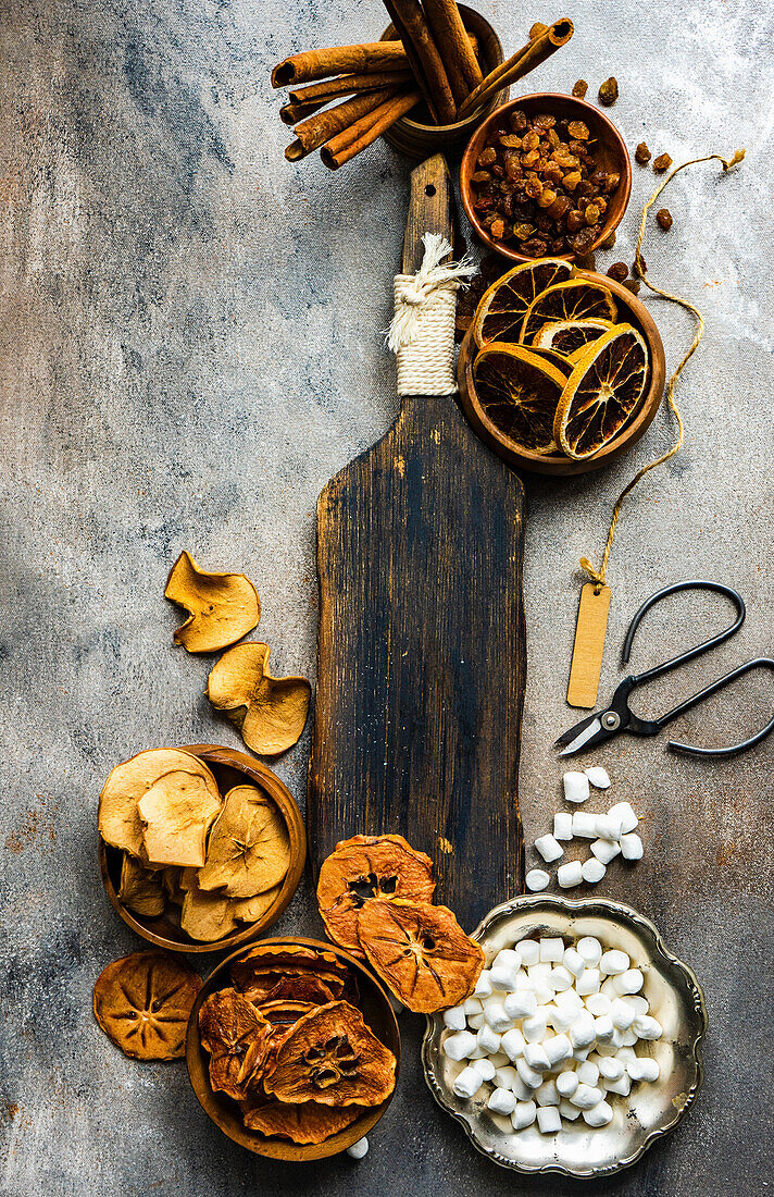 Dried fruit, mini marshmallows and cinnamon sticks on vintage wooden board