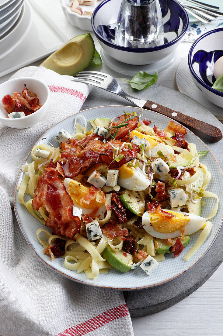 Protein salad with egg, bacon and avocado on pasta