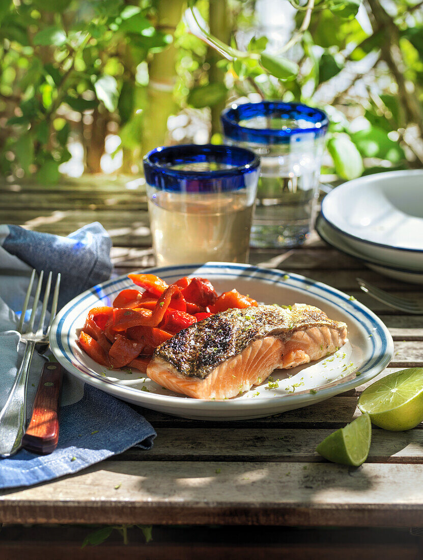 Gegrillter Lachs mit rotem Paprikagemüse auf Tisch im Freien