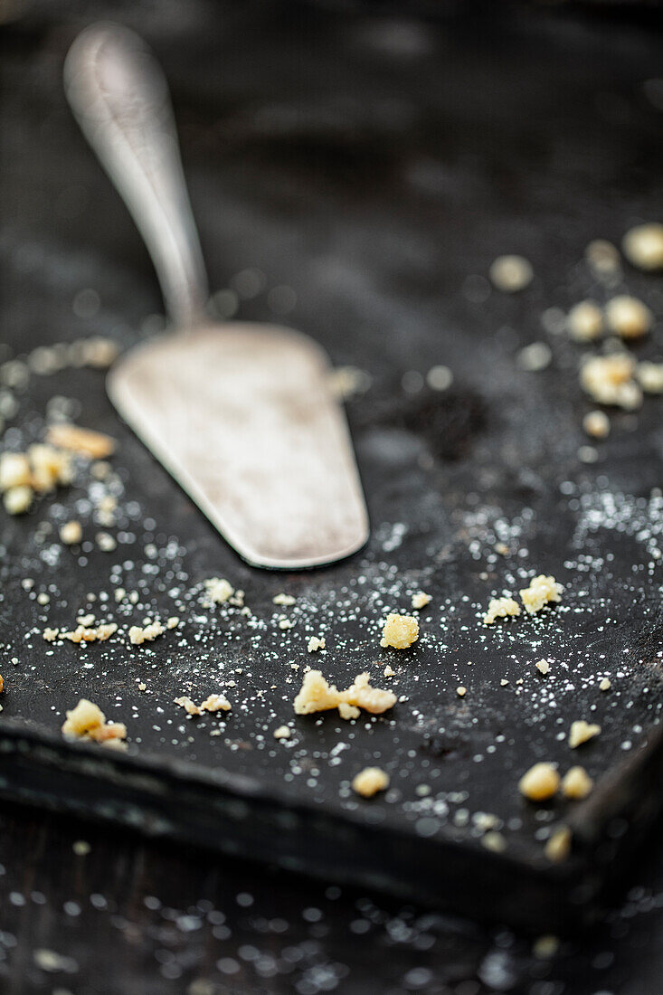 Leeres Kuchenblech mit Kuchenheber und Streuseln