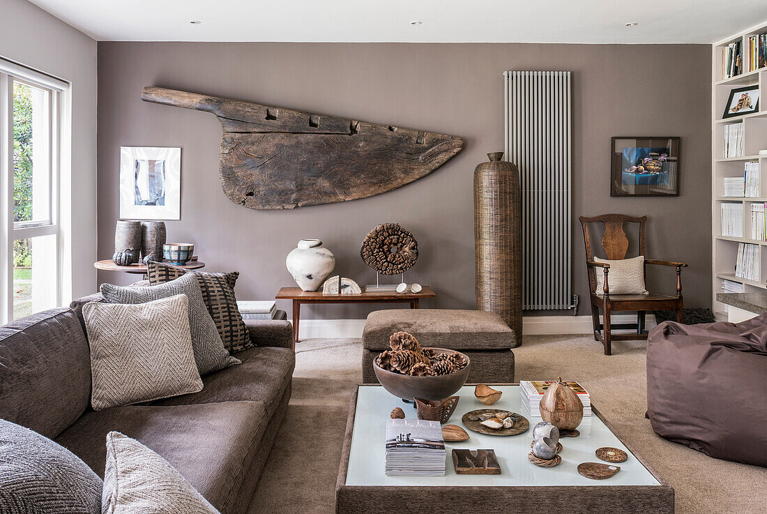 Sofa mit Couchtisch, altes Ruder an der Wand und hohe Korbvase im Wohnzimmer