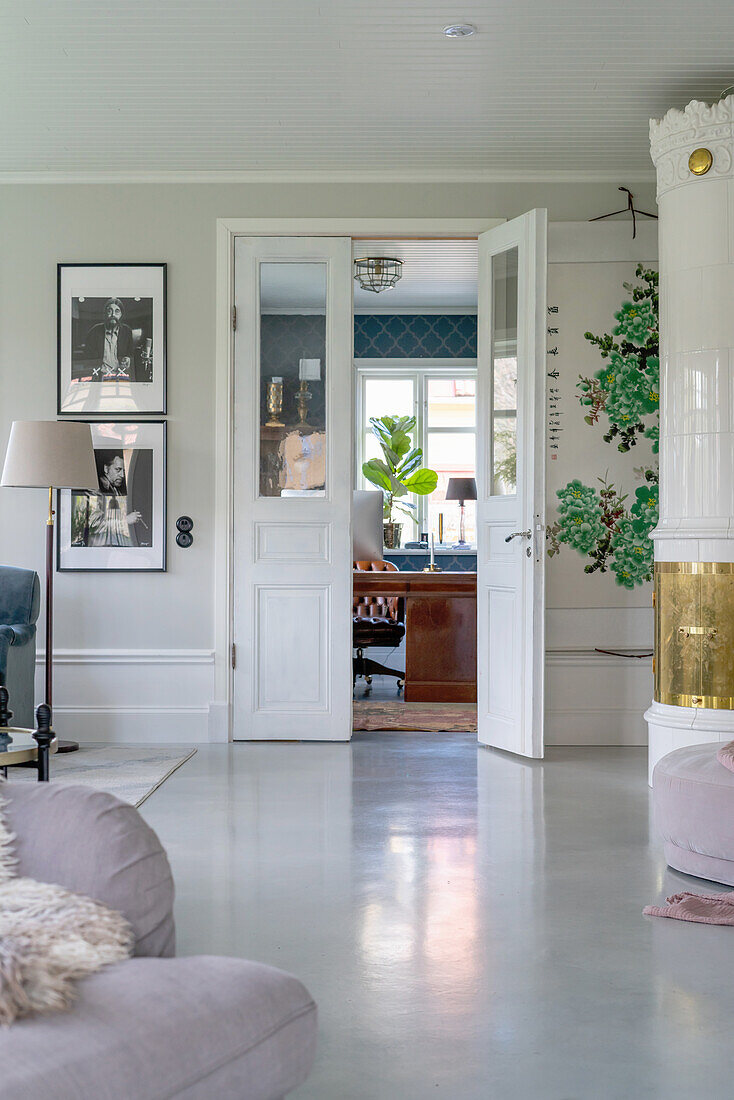 Tiled stove in living room with polished concrete floor: view through open French doors into the study