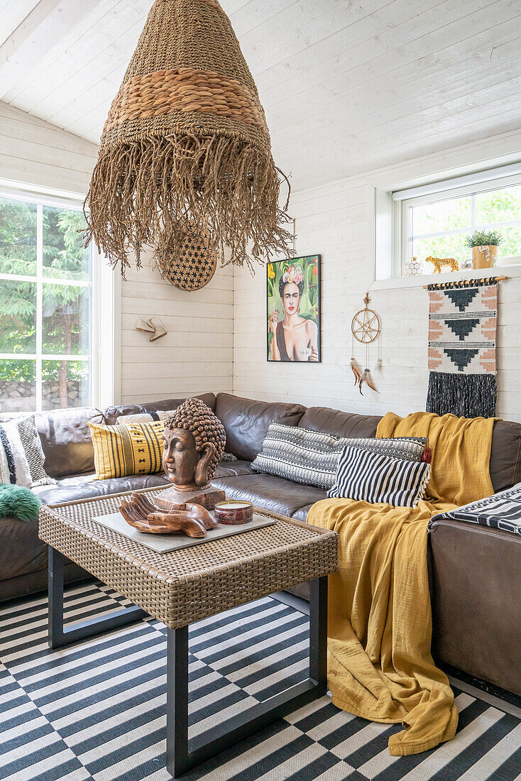 Buddha head on coffee table, above it sea grass lamp and leather sofa in the living room