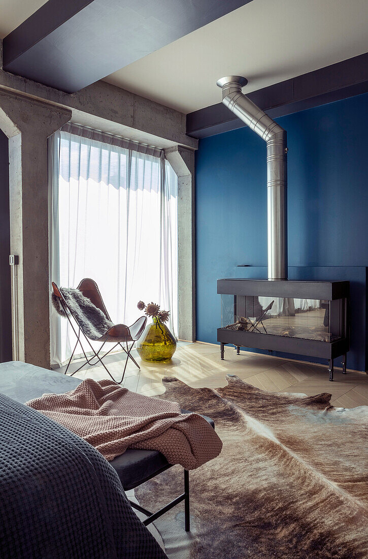 Kaminofen vor blauer Wand im Zimmer mit Tierfellteppich