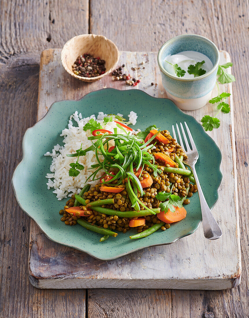 Linsencurry mit grünen Bohnen und Karotten serviert mit Reis