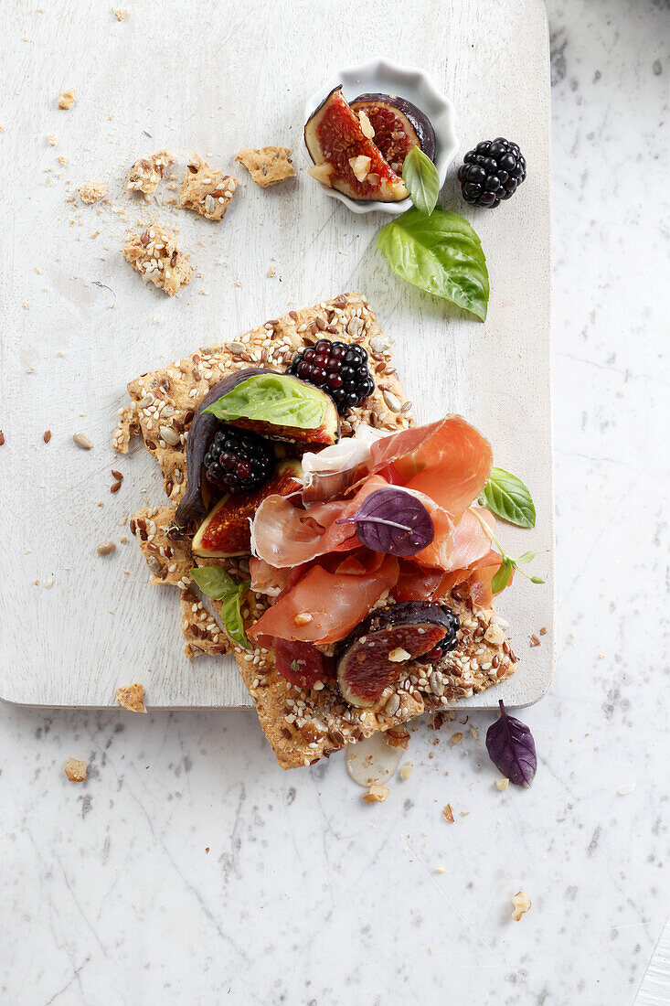 Healthy crispy bread with Parma ham, blackberries and figs
