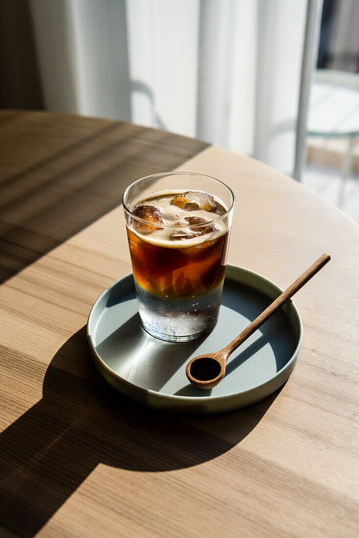 Eiskaffee mit Tonic auf Tisch am Fenster