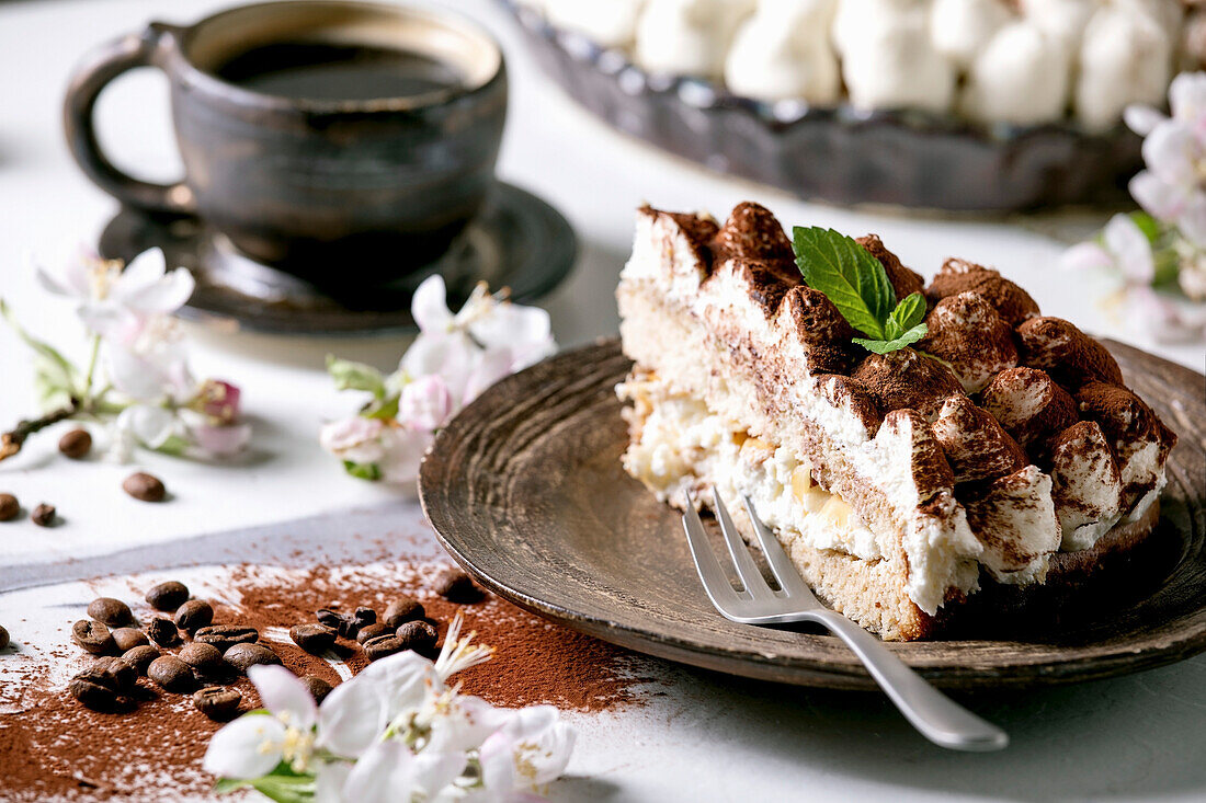 Slice of homemade gluten free tiramisu, sprinkled with cocoa powder decorated with blooming apple tree