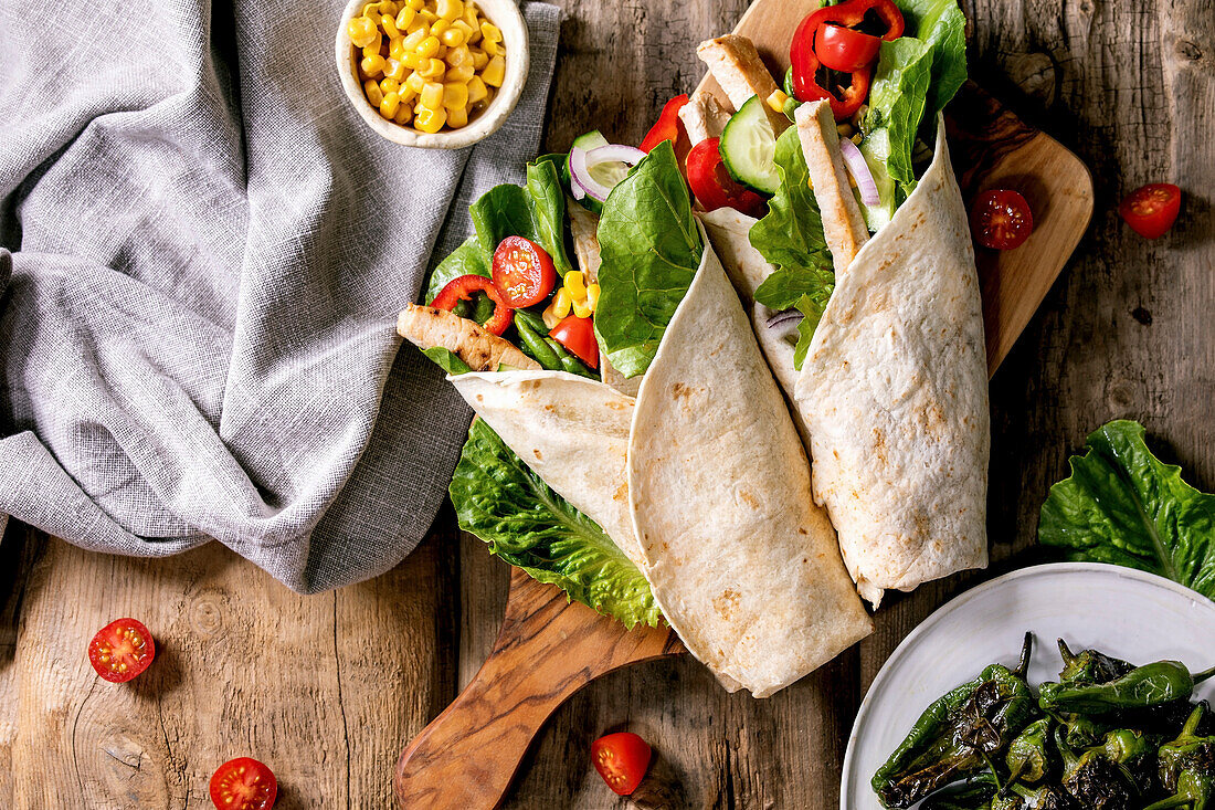 Traditional mexican tortila wrap with pork meat and vegetables, served with grilled green peppers jalapenos and corn