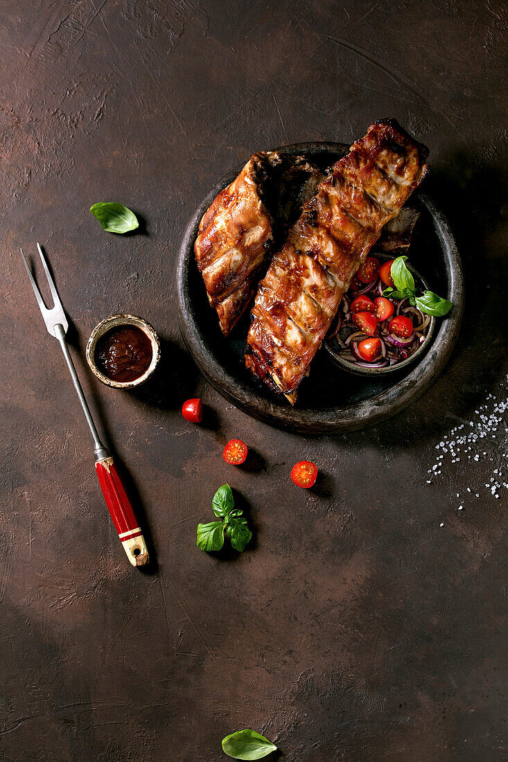 Grilled pork ribs, served with marinated onions, cherry tomatoes, basil and barbeque sauce