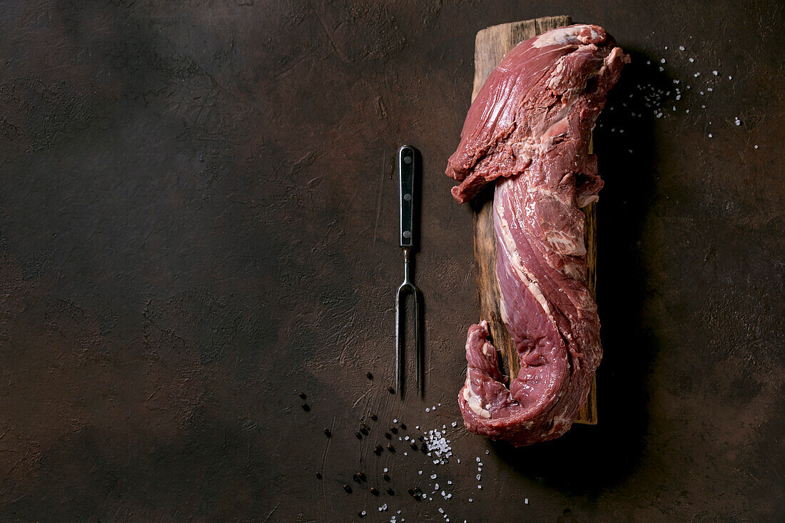 Frisches Rinderfilet auf Holzbrett daneben Fleischgabel