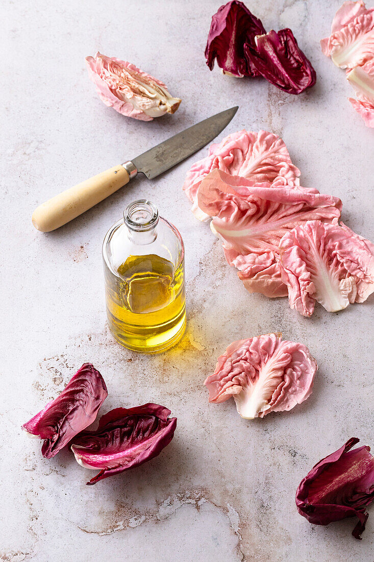 Radicchio leaves, olive oil and a knife on a marble background