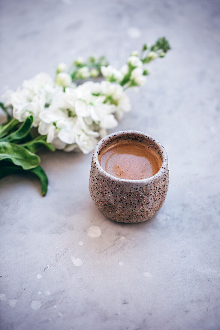 Ein Becher Kaffee im Hintergrund Blütenzweige