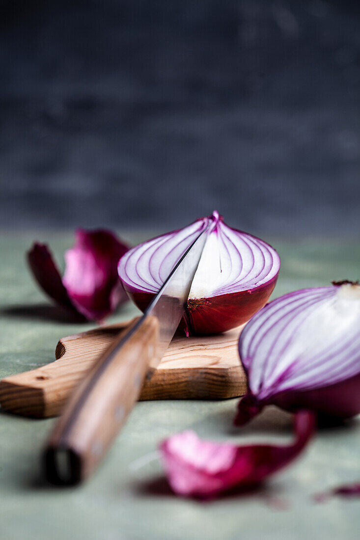 Red onions with a knife on a chopping board