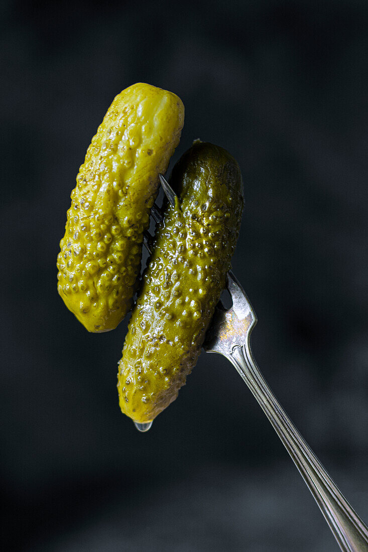 Two pickled cucumbers skewered on a fork