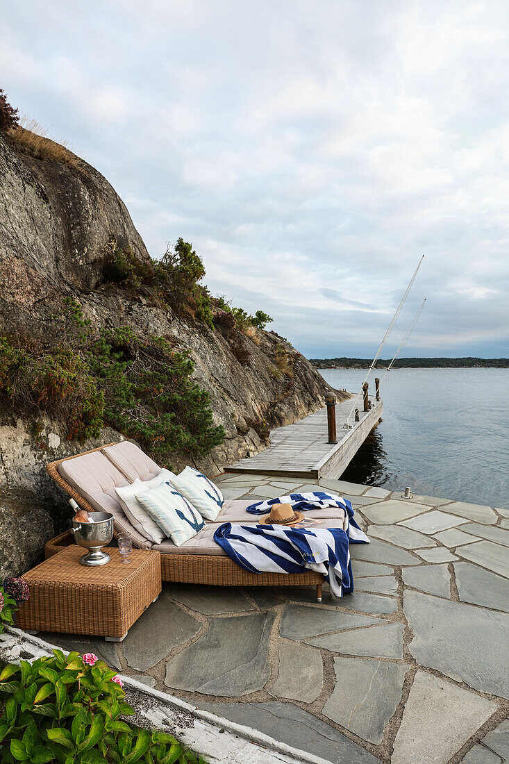 Wicker loungers on terrace with jetty by the sea