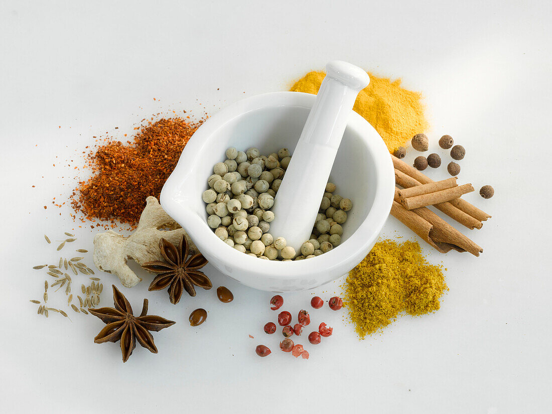 Different kinds of spices, in a mortar and spread around it
