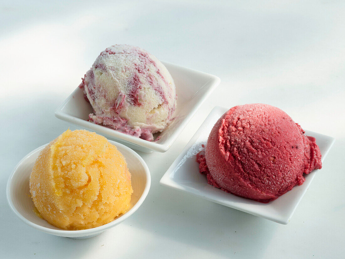 Three small bowls with one scoop of ice cream each
