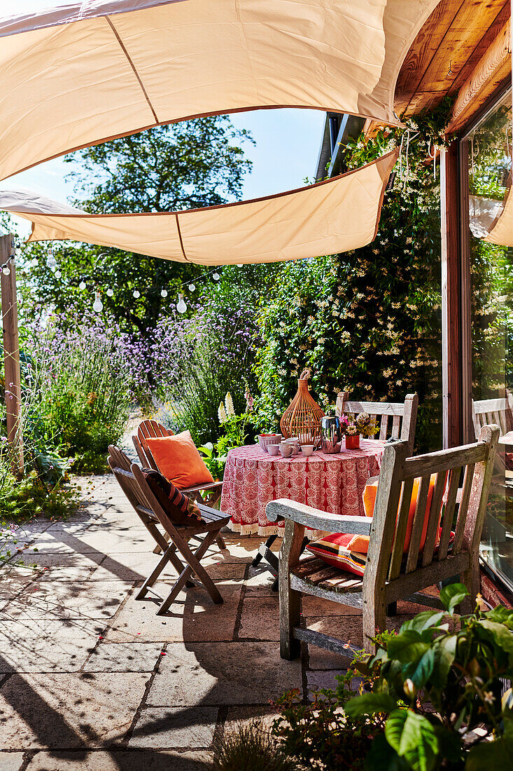 Round table and wooden chairs under awning on terrace