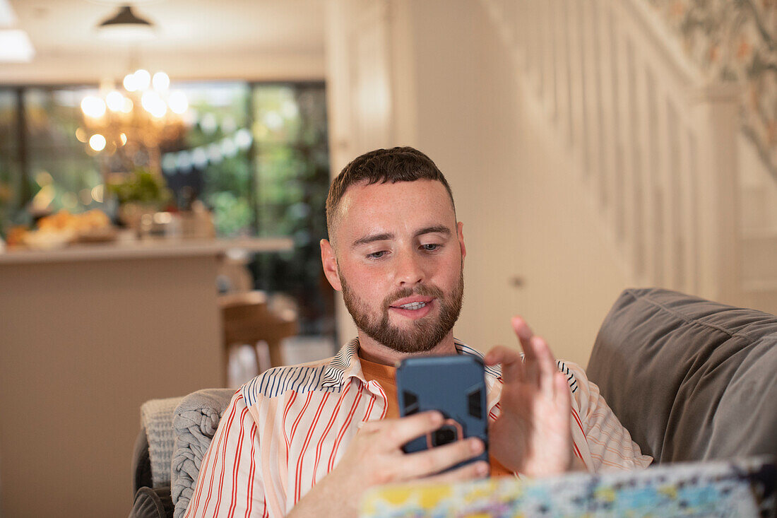 Young man using smart phone on sofa