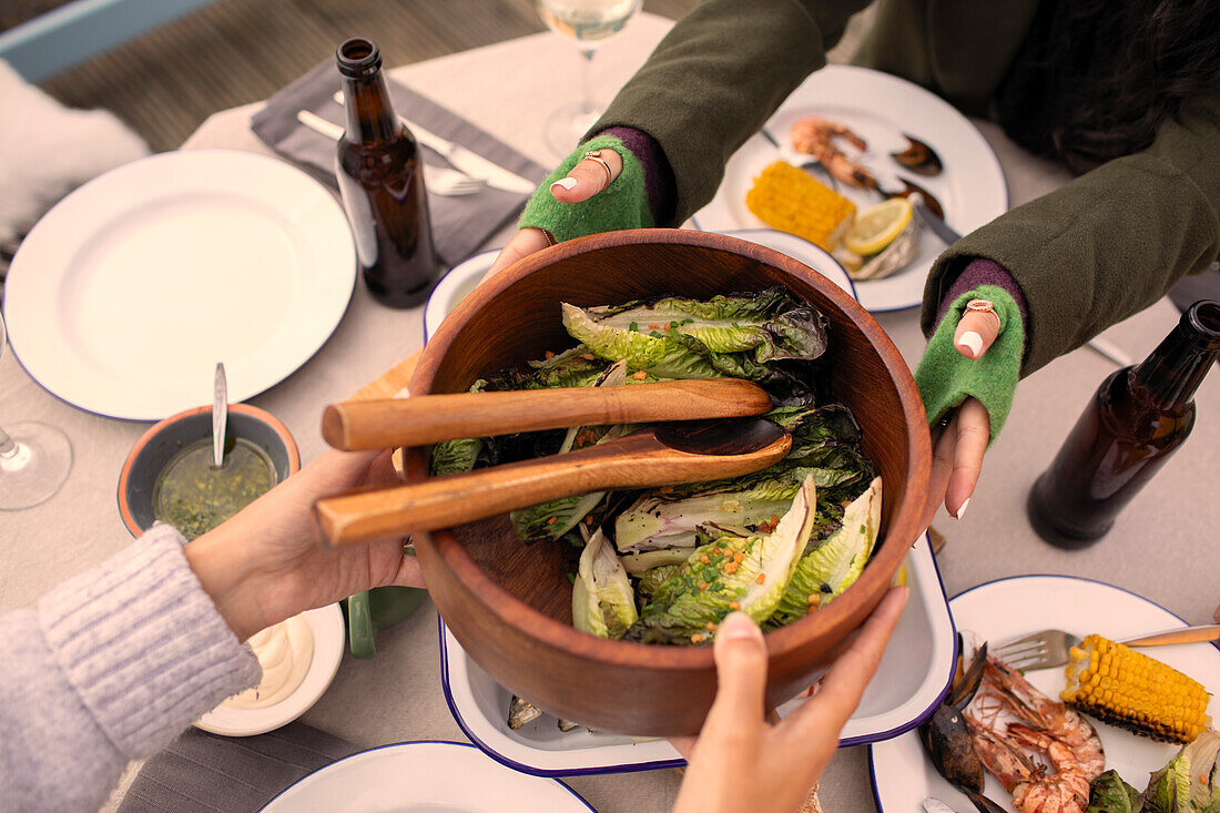 Friends passing salad over patio table