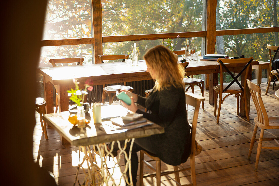 Businesswoman working at sunny cafe table